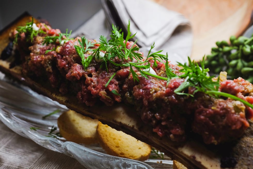 Steak tartar de vaca sobre su tuétano asado en brasas de carbón