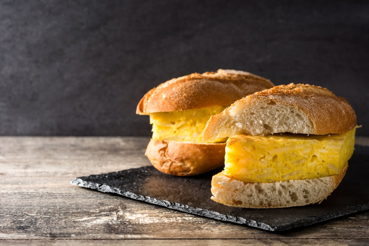 Bocadillo de tortilla española. Spanish potato omelette sandwich on wooden table